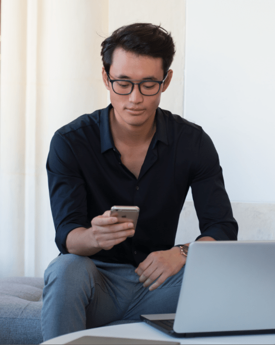 Bărbat purtând lentile Essilor cu un design de lentilă Eyezen în timp ce se uită pe smart phone